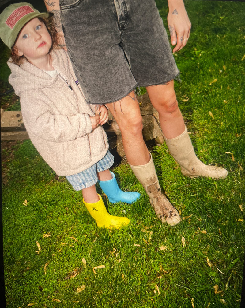 Child wearing Kamik Stomp rain boots with mother wearing Kamik Miranda rain boots in their yard
