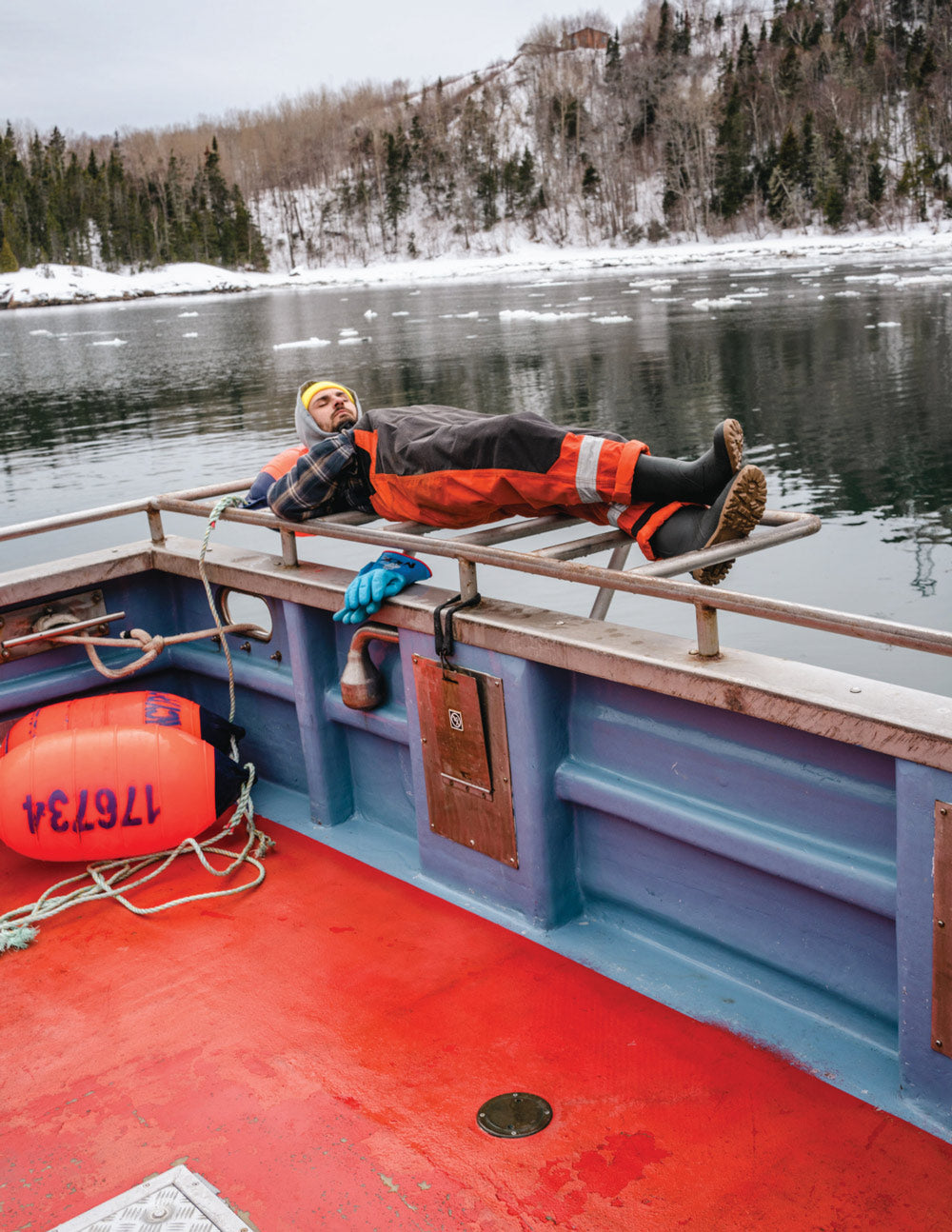 Fisherman lying on a boat wearing Kamik Work Horse waterproof work boots
